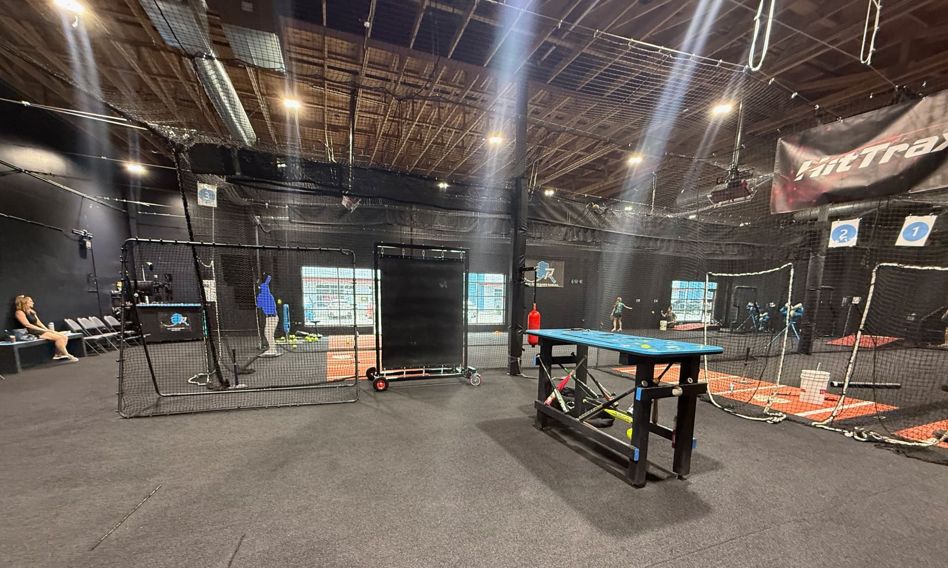 Interior view of Peak Performance Baseball and Softball showing multiple indoor training tunnels, HitTrax equipment, pitching areas, and baseball and softball training space.